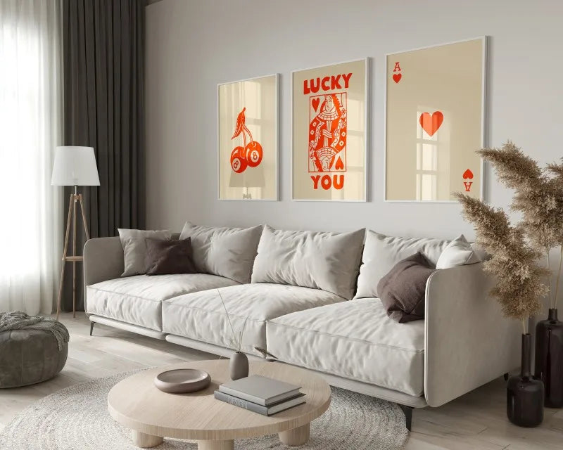 A modern living room features a light sofa, decorative pillows, and framed art prints on the wall.