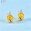 Two small glass bottles with handles and corks filled with yellow liquid, featuring a crow silhouette label.