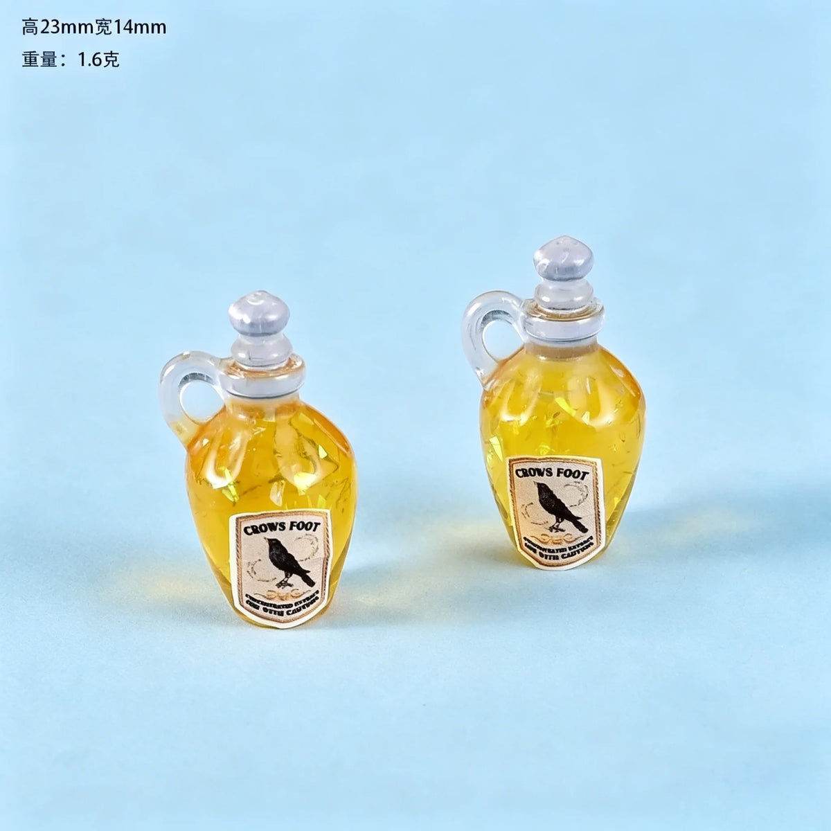 Two small glass bottles with handles and corks filled with yellow liquid, featuring a crow silhouette label.