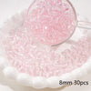 A clear glass bowl filled with pink round spacer beads for jewelry making, displayed on a white dish.