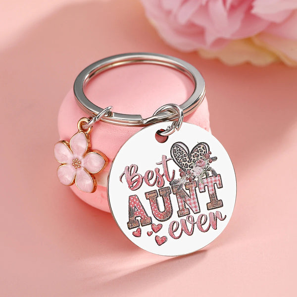 An elegant silver stainless steel keychain featuring a floral charm and the text Best Aunt ever on a round tag.