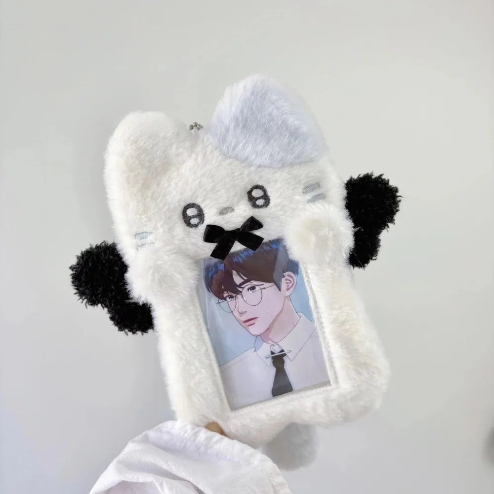 A white fluffy plush toy shaped like a bear holding a framed photo of a male character.