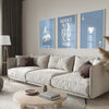 A modern living room features a light sofa and wooden coffee table with decorative art prints on the wall.