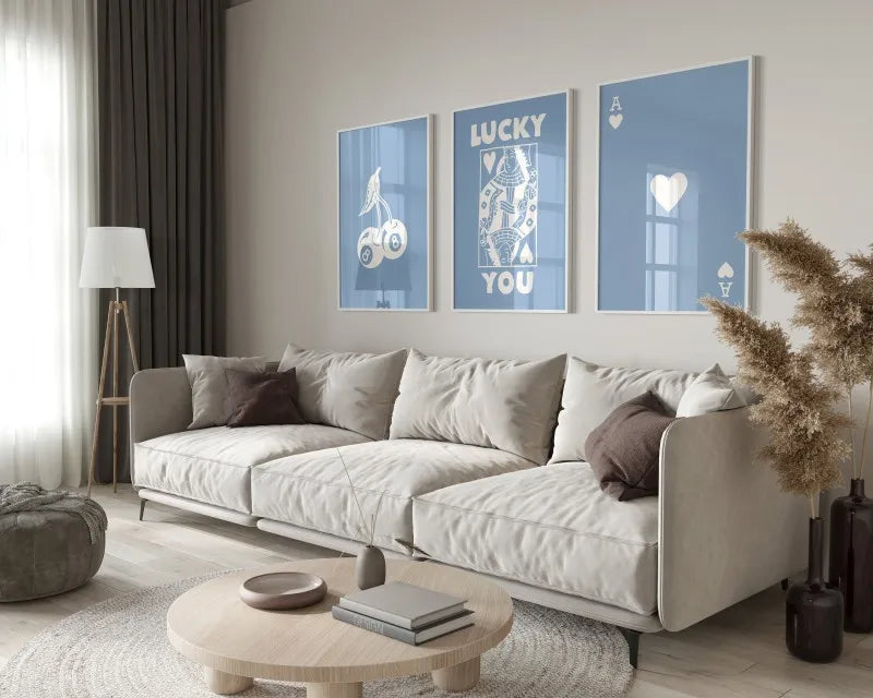 A modern living room features a light sofa and wooden coffee table with decorative art prints on the wall.