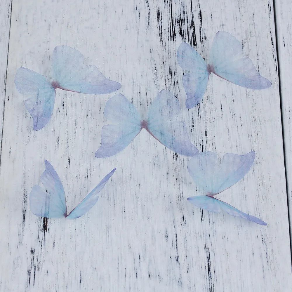 Light blue organza butterfly embellishments scattered on a white wooden surface.