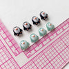 A collection of resin mini penguin figurines arranged along a pink ruler.