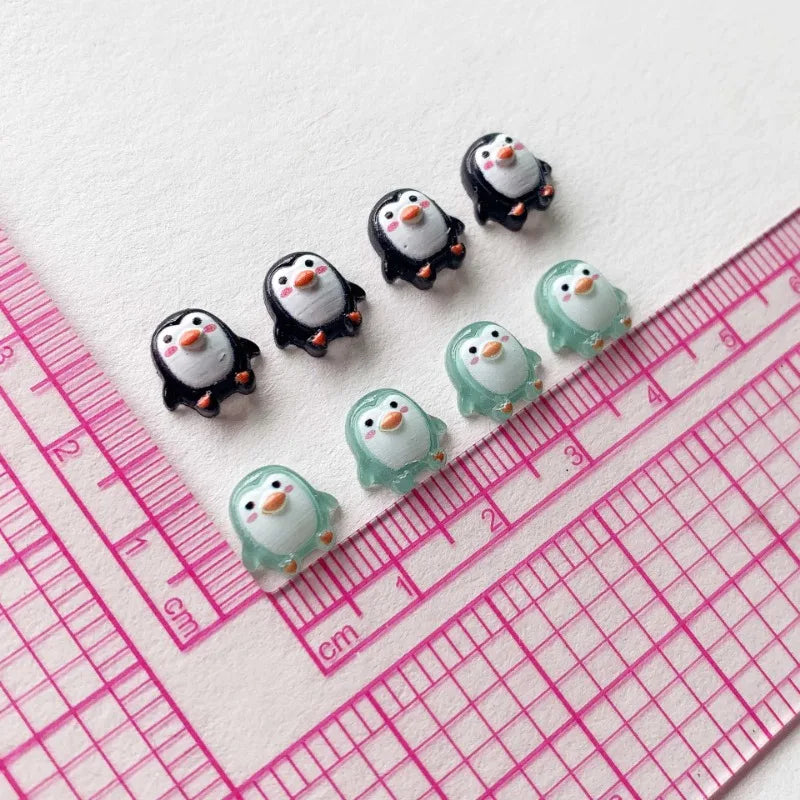 A collection of resin mini penguin figurines arranged along a pink ruler.