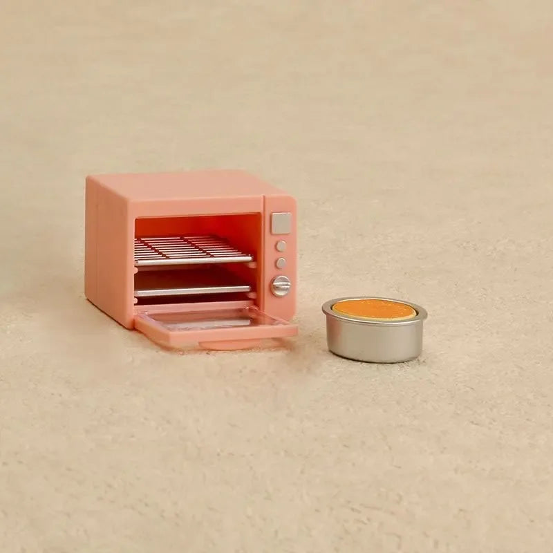 A pink miniature kitchen appliance set with a visible oven rack and a small silver tin.