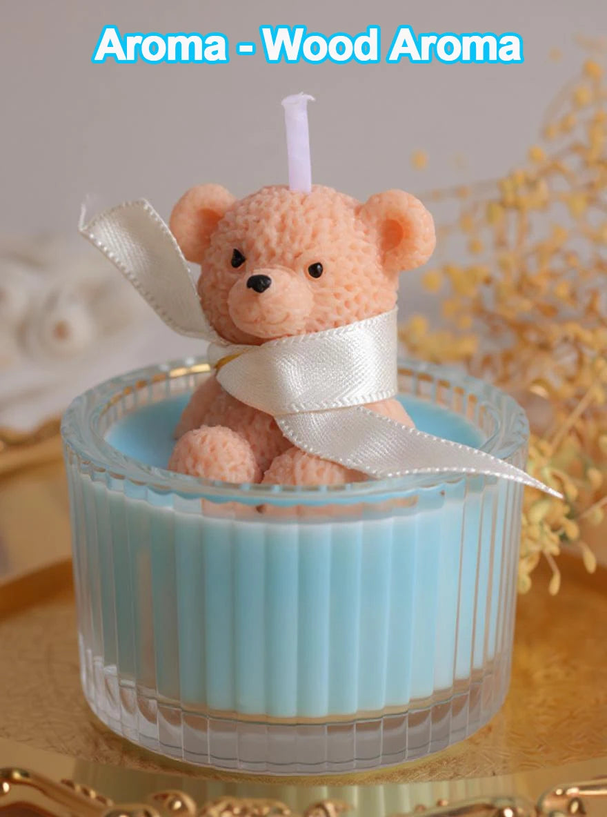 A fluffy orange teddy bear candle in a glass jar with a white ribbon, set against a blurred background.