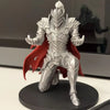 A silver 3D printed knight figure in armor with a red cape standing on a black base.