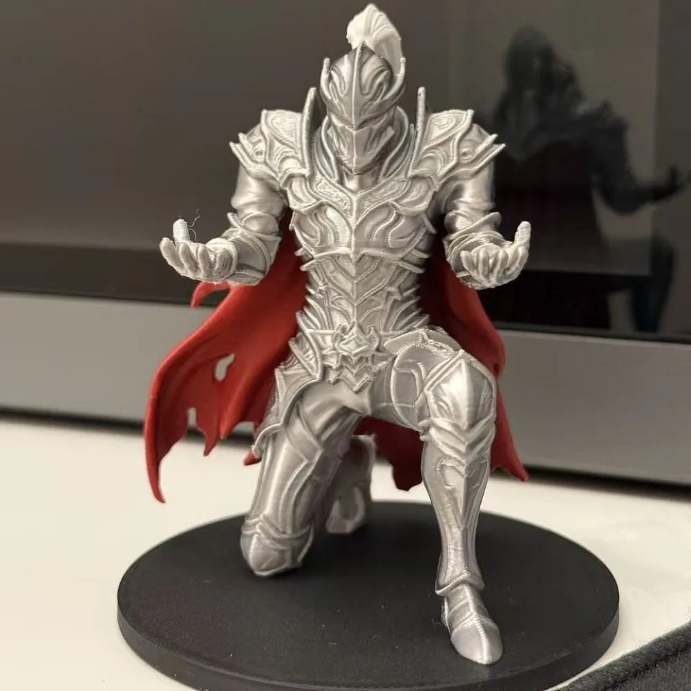 A silver 3D printed knight figure in armor with a red cape standing on a black base.