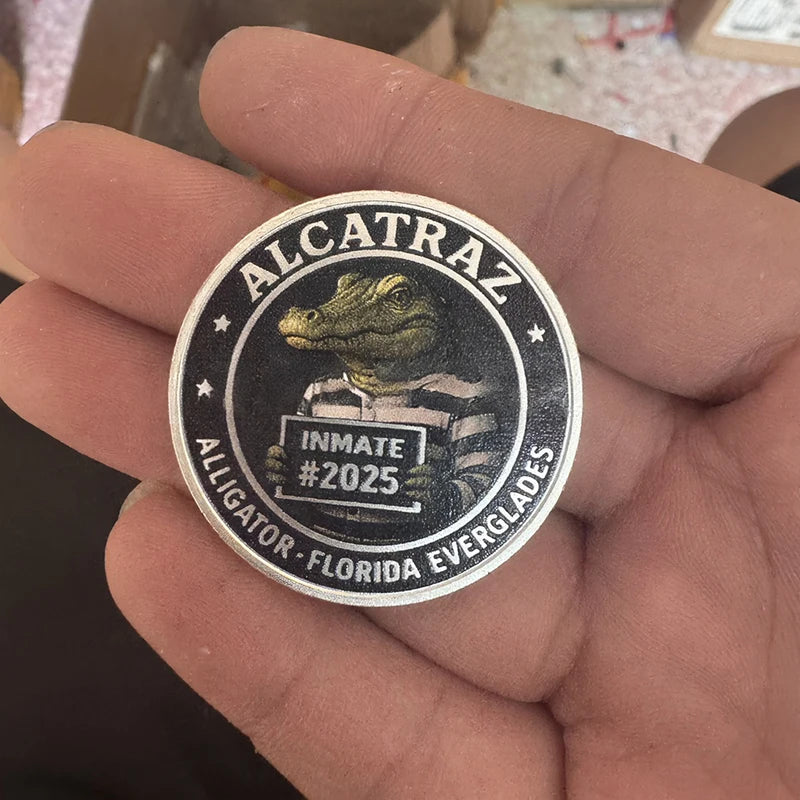 A hand holds an Alcatraz themed coin featuring an alligator design and the text Inmate #2025 Florida Everglades.