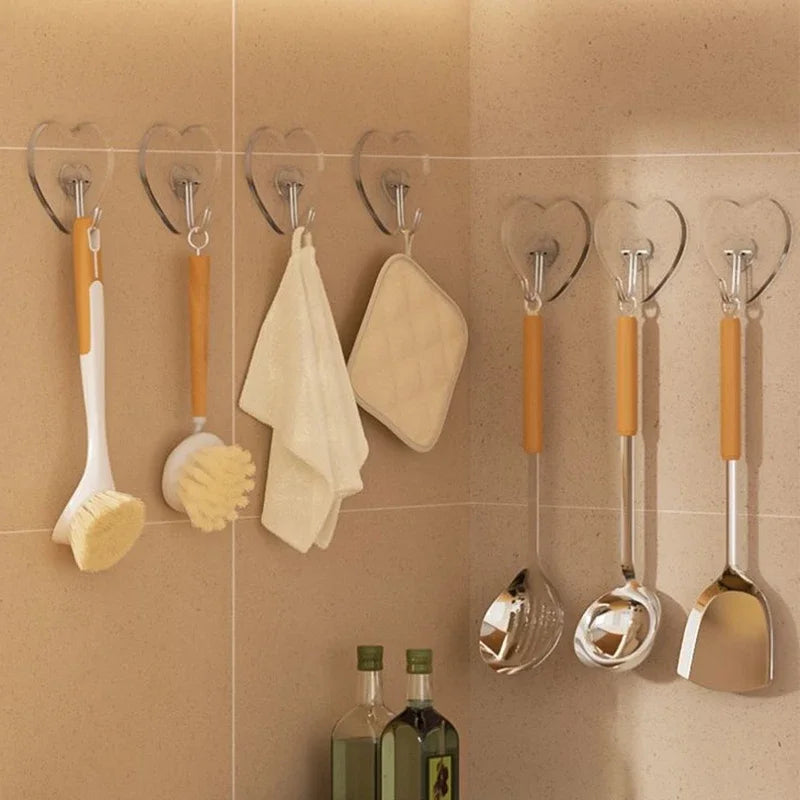 A set of ten transparent self-adhesive hooks for hanging kitchen utensils on a beige tiled wall.