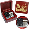 A red wooden music box with an open lid and a gold-colored box featuring the text The Godfather.