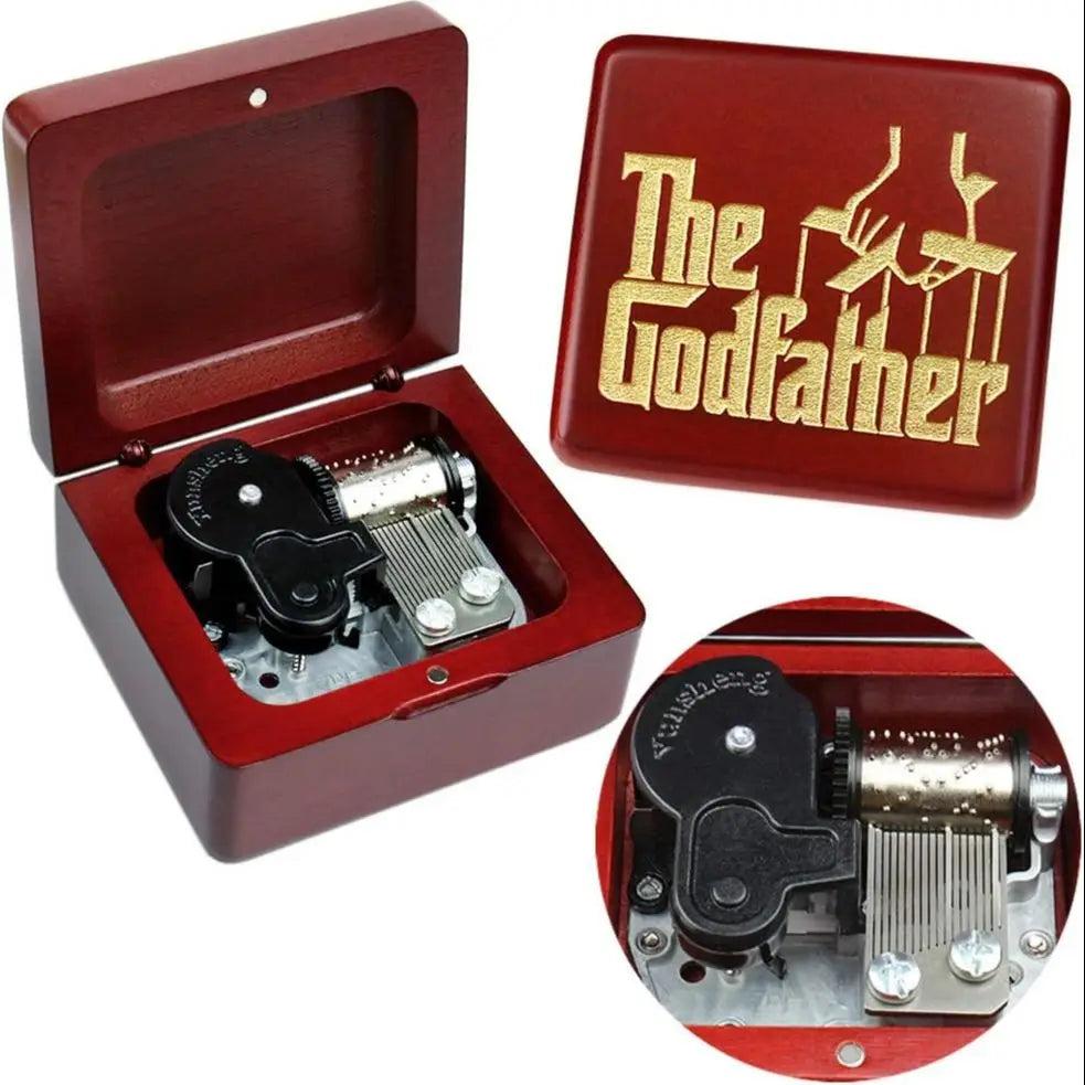A red wooden music box with an open lid and a gold-colored box featuring the text The Godfather.
