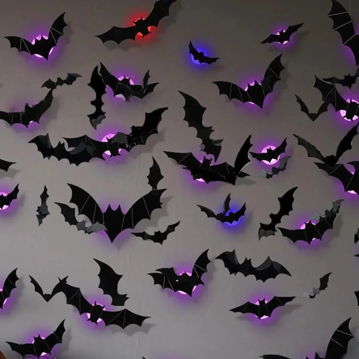 Decoración de pared con siluetas de murciélago y araña negras iluminadas por luces LED moradas y azules.