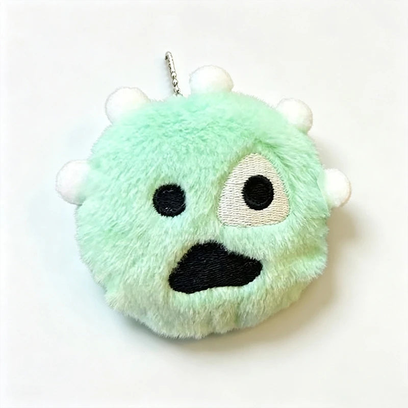 A light green fuzzy plush keychain shaped like a face with black eyes and mouth.