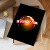 A dark poster featuring the text The world is yours in pink lettering, displayed on a light wooden background.