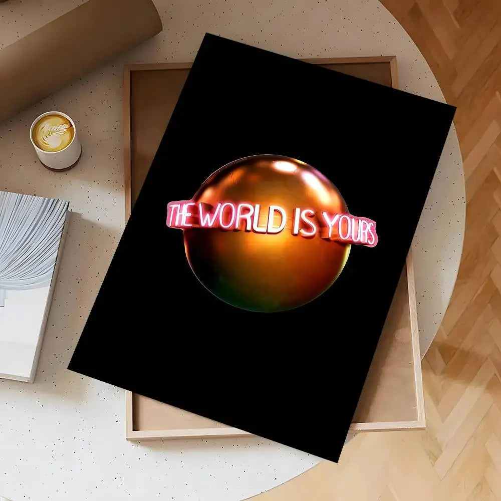 A dark poster featuring the text The world is yours in pink lettering, displayed on a light wooden background.