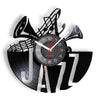 A black wall clock shaped like the letter J with a vinyl record design and a clock face.
