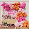 A vibrant balloon garland featuring pink and orange balloons decorating a backdrop for a party.