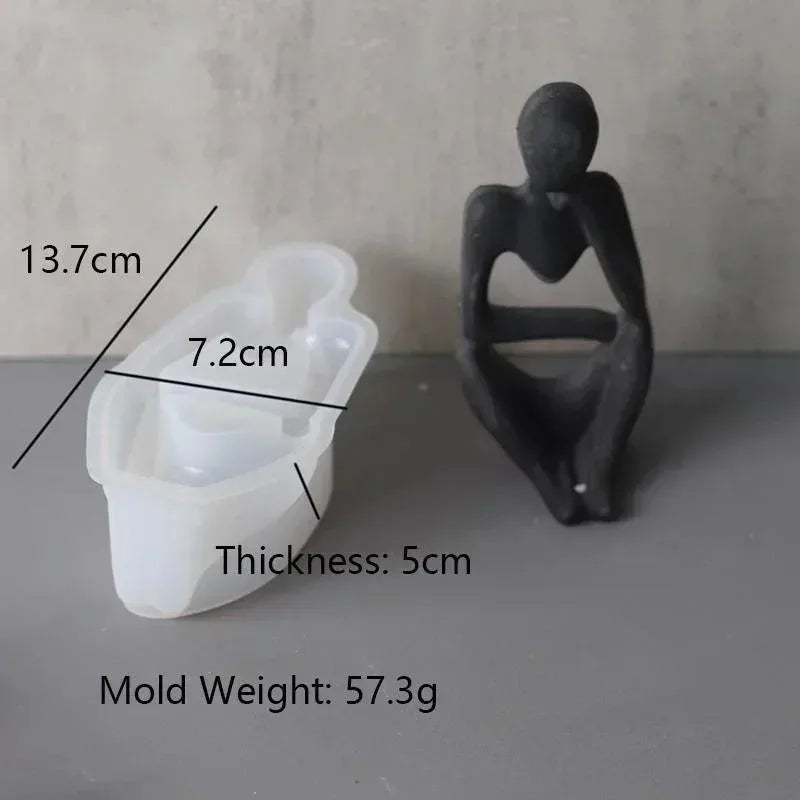 A white silicone mold with dimensions 13.7cm by 7.2cm and a thickness of 5cm, next to a dark, abstract silicone mold.