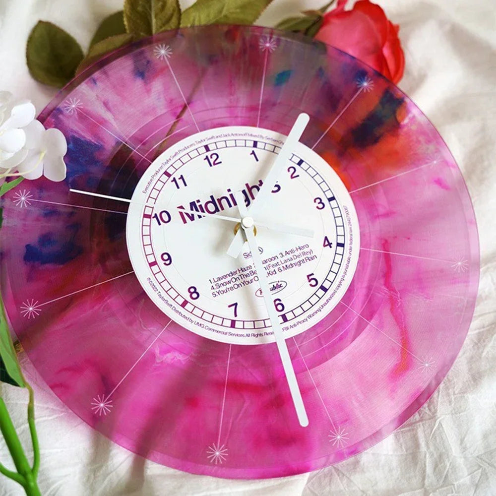 A vintage vinyl record wall clock with a transparent, pink and purple marbled cover displaying the time.