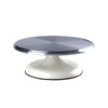 A round, silver aluminum cake turntable with a white pedestal base.