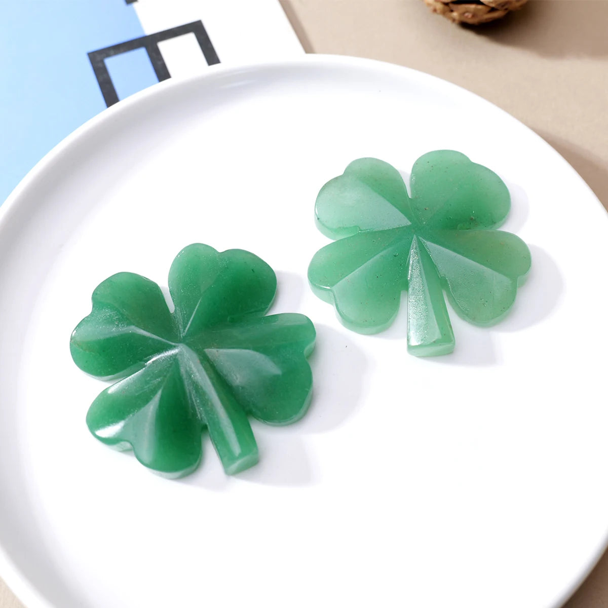 A small, translucent green four-leaf clover crystal statue resting on a white plate.