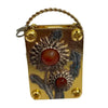 A small brass metal box with a wire loop, featuring pressed dried flowers and round amber-colored elements.