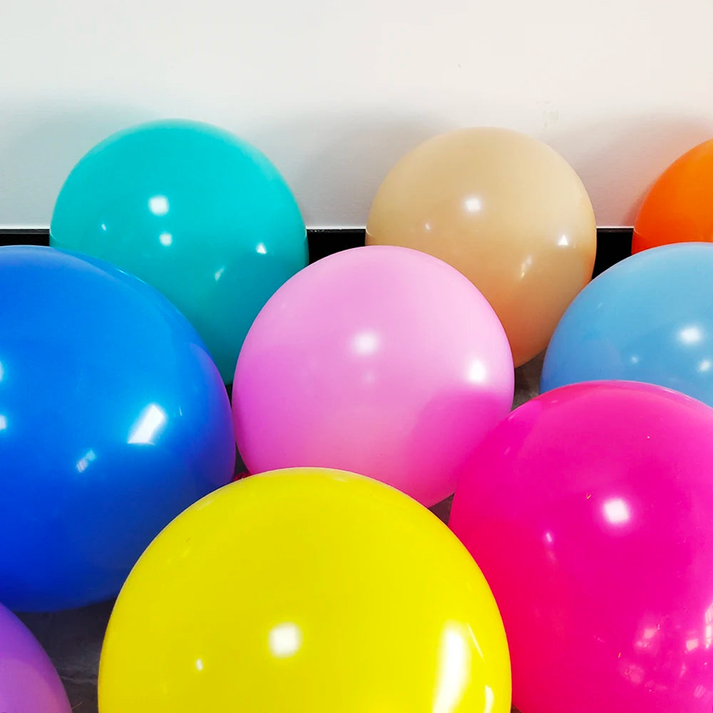 A collection of matte latex balloons in various bright colors including blue, pink, yellow, and orange arranged in a tray.