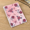 A pink spiral notebook featuring a floral pattern of roses and butterflies for sticker collecting.