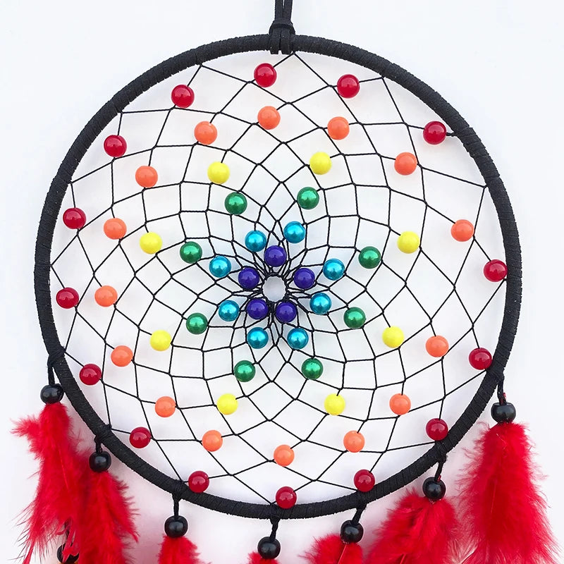A black mesh dream catcher with colorful beads and red feathers hanging from it.
