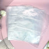 Una pila de hojas de carpetas transparentes para photocards de Kpop, sobre una superficie rosa.