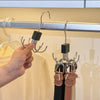A hand is holding a multi-claw hanger with a black hook for closet organization.