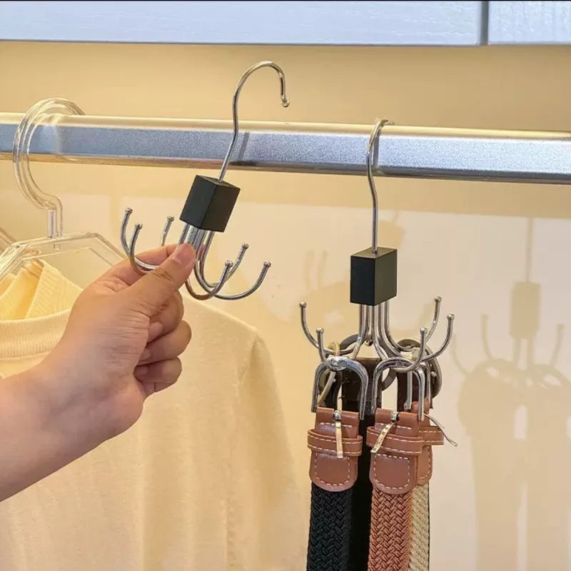 A hand is holding a multi-claw hanger with a black hook for closet organization.