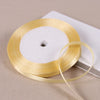 A golden satin ribbon spool with a white center is shown on a light background.