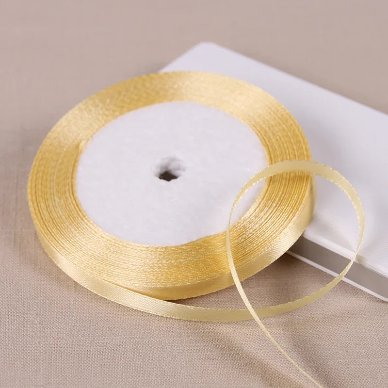 A golden satin ribbon spool with a white center is shown on a light background.