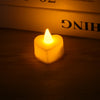 A glowing yellow heart-shaped tealight candle resting on a wooden surface.