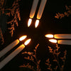 A close-up view of several glowing white LED taper candles arranged in a circular pattern against a dark background.