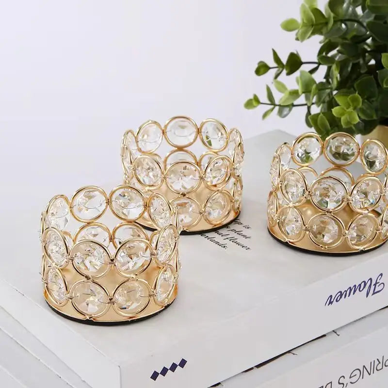 A set of gold-toned crystal candle lantern holders with round glass elements displayed on a white box.