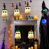 Halloween hanging ghost lights with witch hats decorating a fireplace mantel and dark background