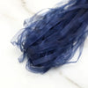 A bundle of dark blue decorative fishtail yarn ribbon laid on a white marble surface.