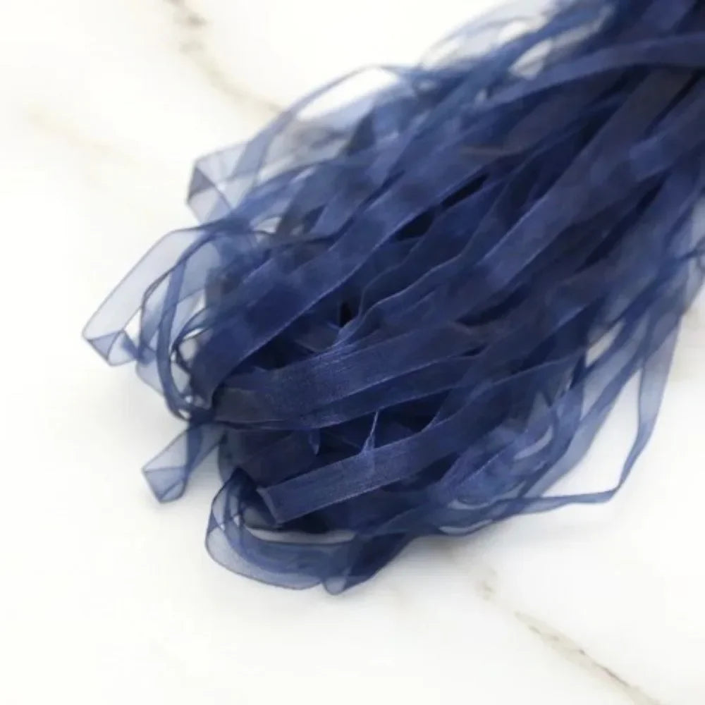 A bundle of dark blue decorative fishtail yarn ribbon laid on a white marble surface.