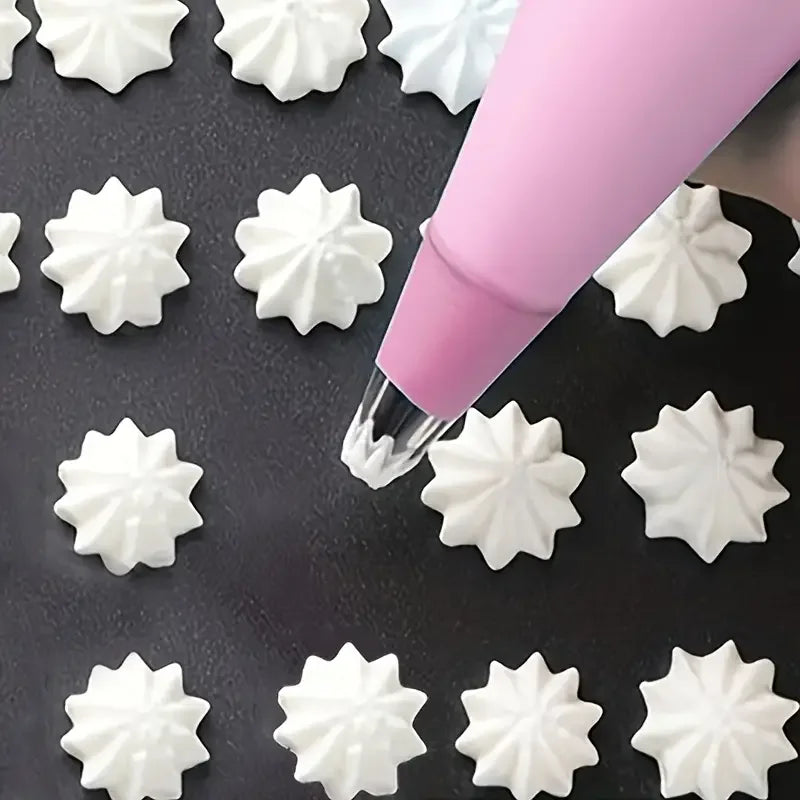 A pink piping bag is shown applying white frosting to a dark surface, surrounded by decorative star-shaped frosting tips.