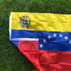 A vibrant Venezuelan national flag banner displayed on green grass.