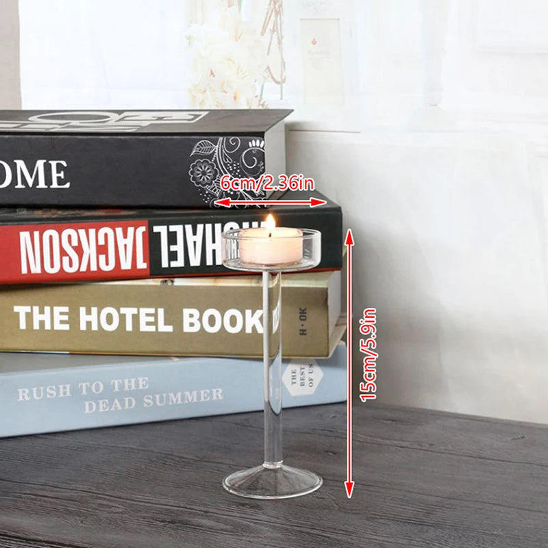 Elegant tall glass candle holder with a lit candle placed among stacked books.