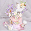 A pink tiered cake decorated with butterfly toppers and floral accents on a white background.