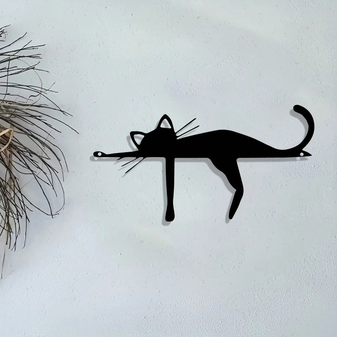 A black silhouette sculpture of a cat mounted on a white wall.