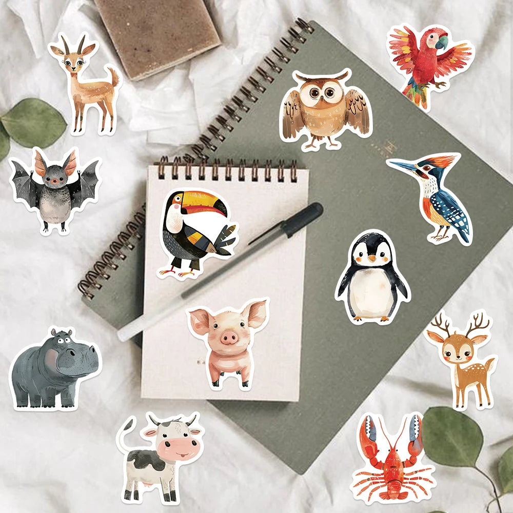 A collection of assorted animal stickers featuring deer, owls, penguins, and other wildlife designs on a gray notebook.